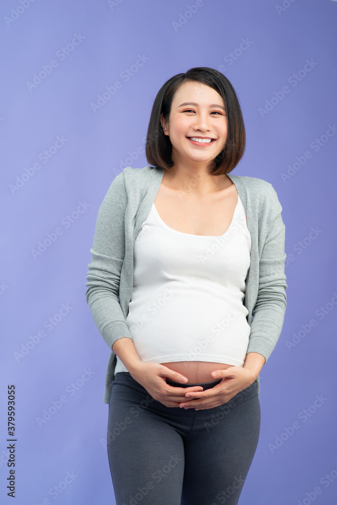 Happy pregnant woman posing on color background