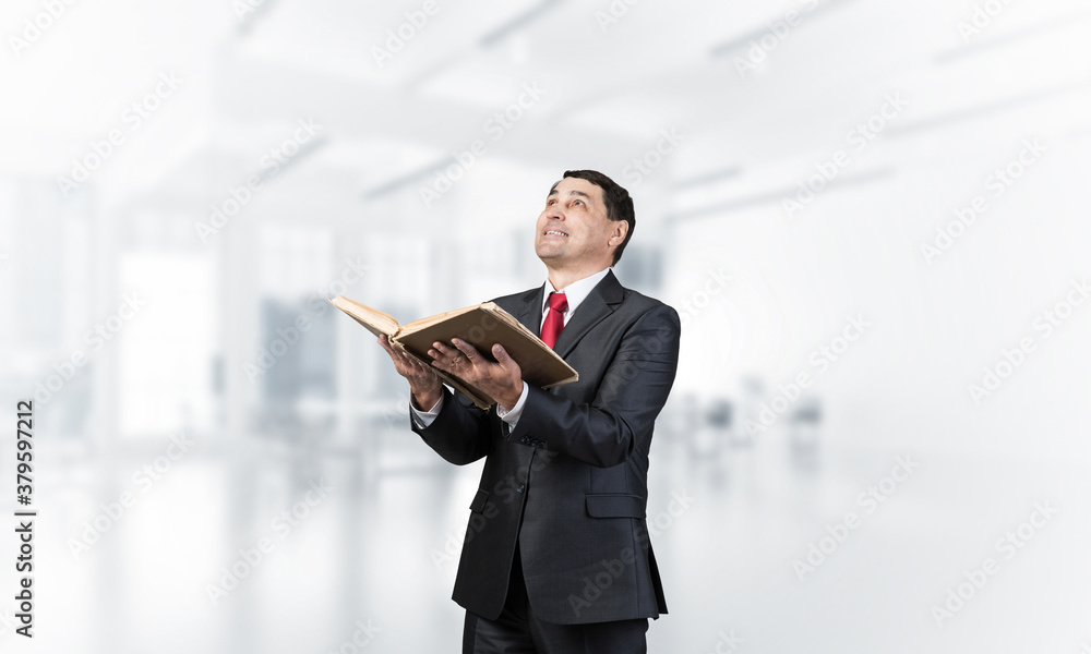 Smiling businessman with open book looking up