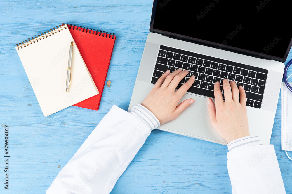 Top view of doctor hands typing at laptop