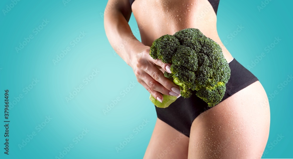 Slim young woman showing healthy vegetable