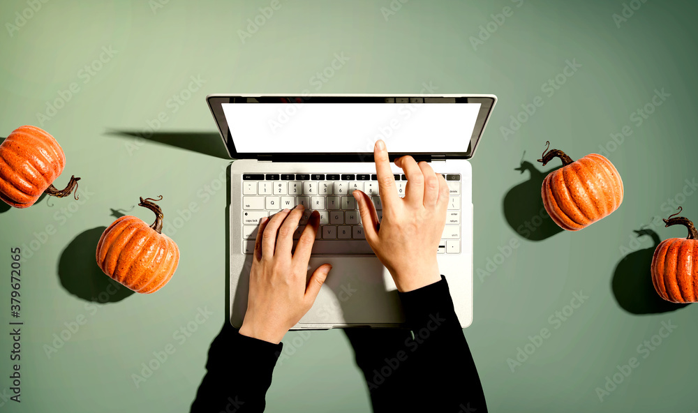 Autumn pumpkins with person using a laptop computer from above