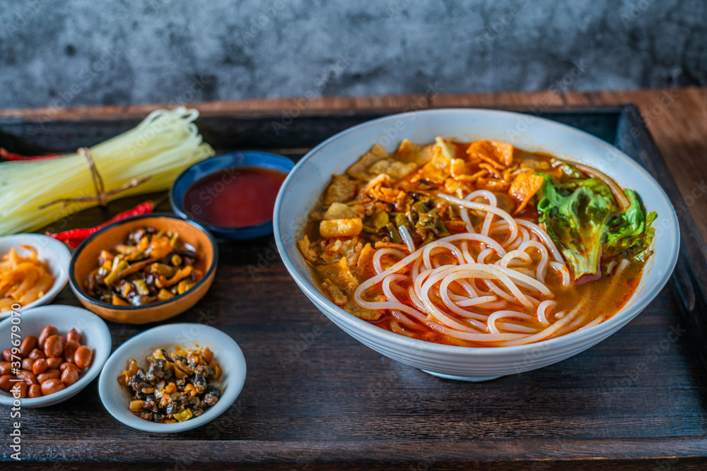 A bowl of snail noodles on a wooden table