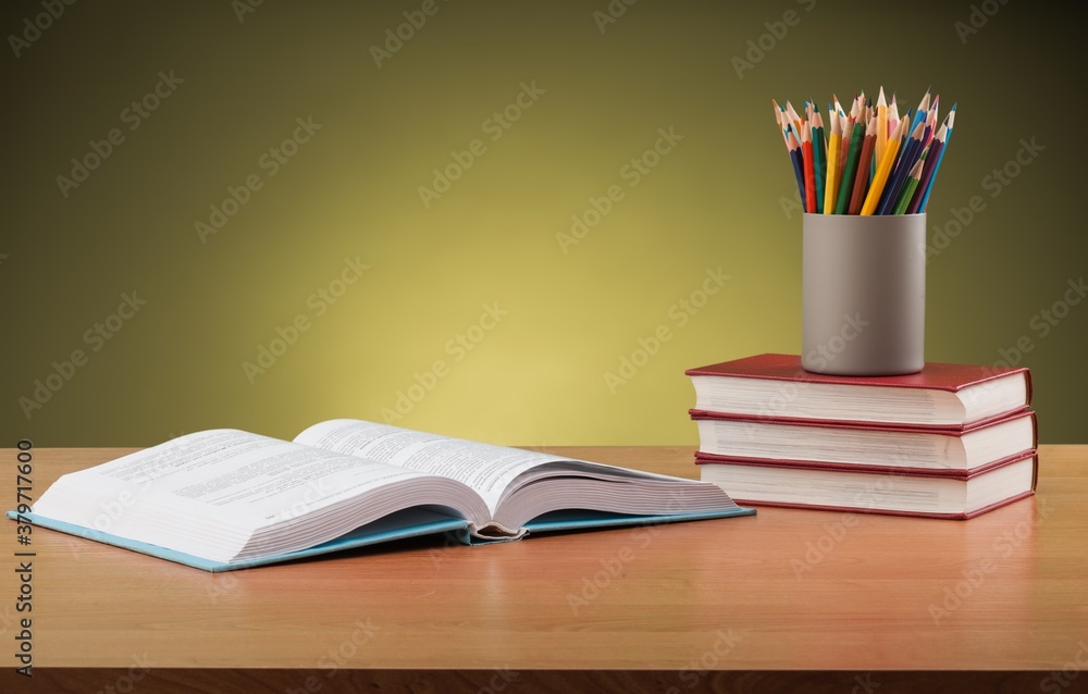 Stack school books with colorful pencils on a desk