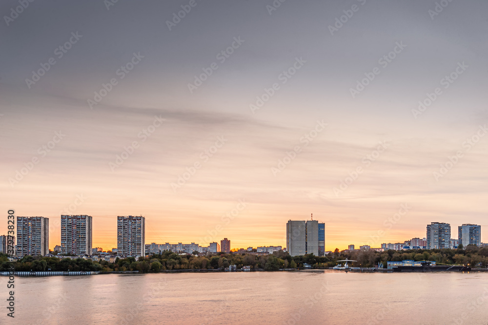 modern city along a river at sunset, panoramic view, golden hour