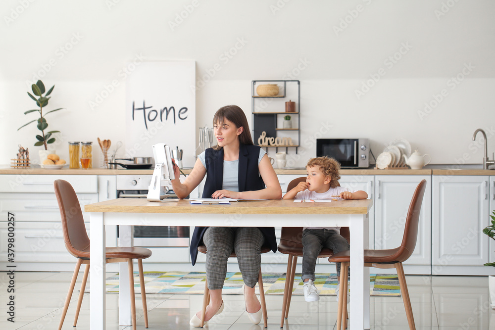 Working mother with little son in kitchen at home