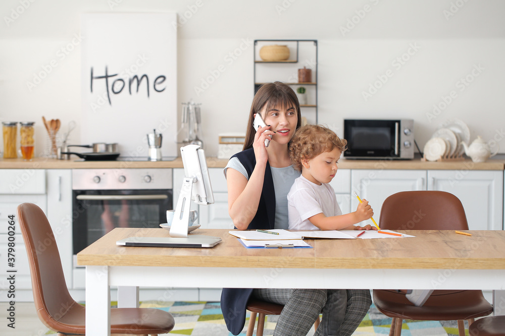 Working mother with little son in kitchen at home