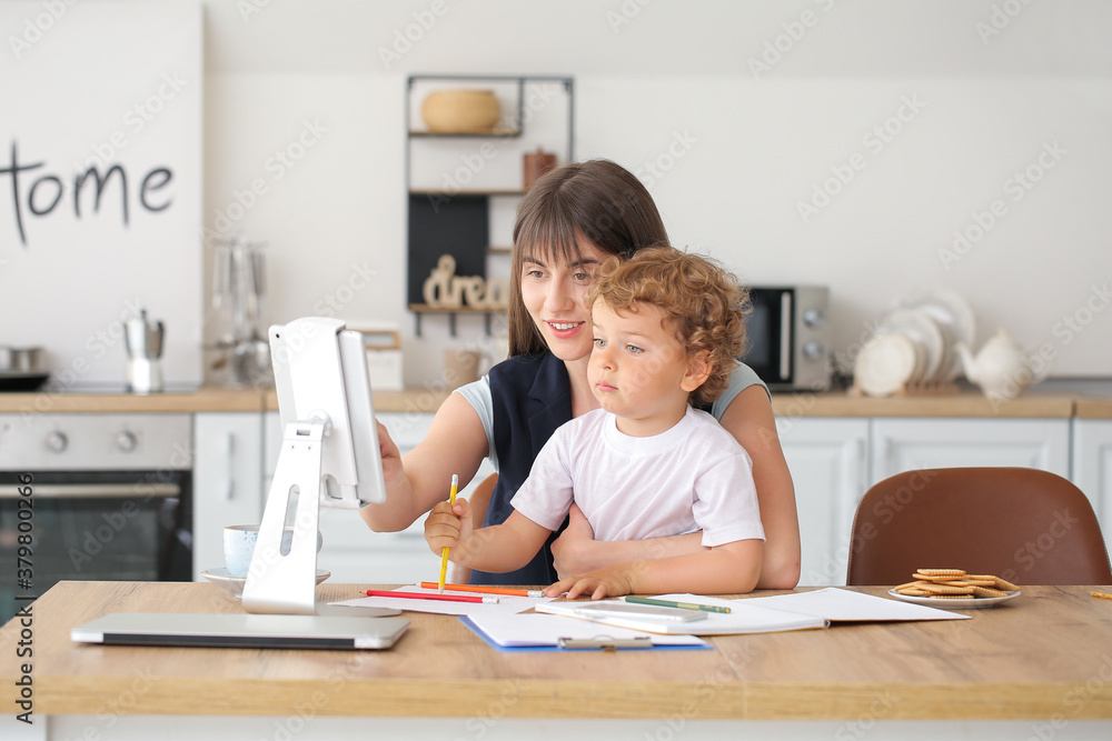 Working mother with little son in kitchen at home