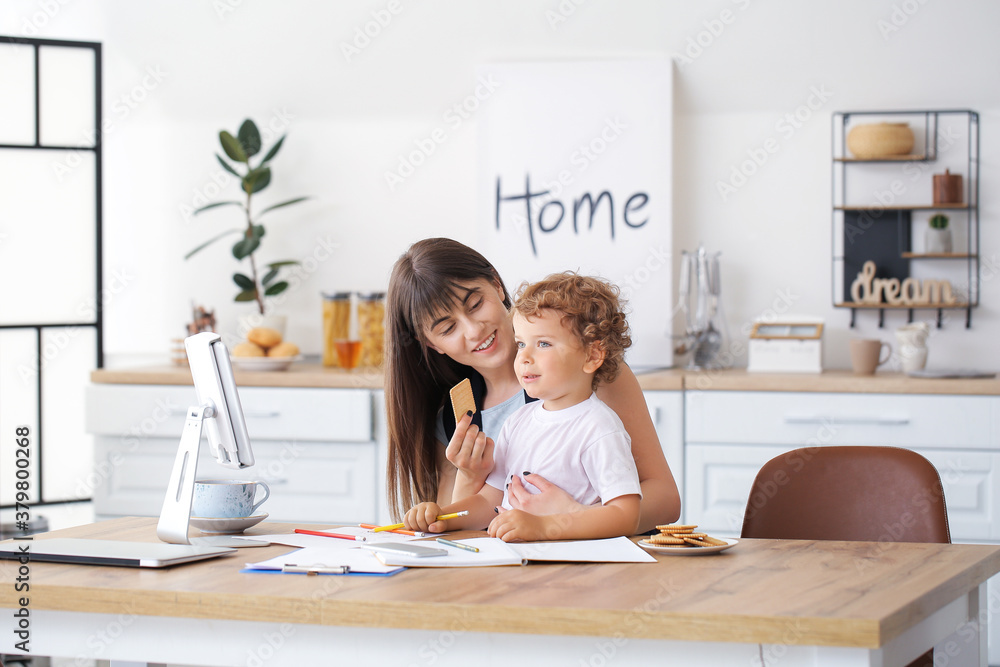 Working mother with little son in kitchen at home