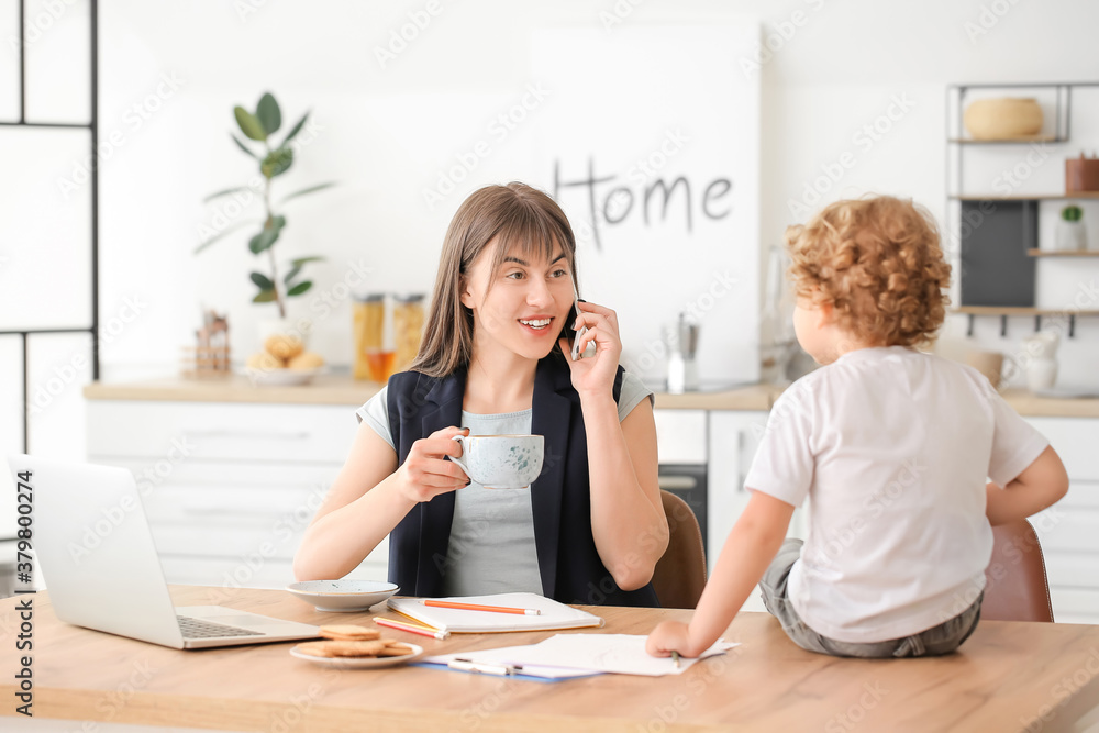 Working mother with little son in kitchen at home