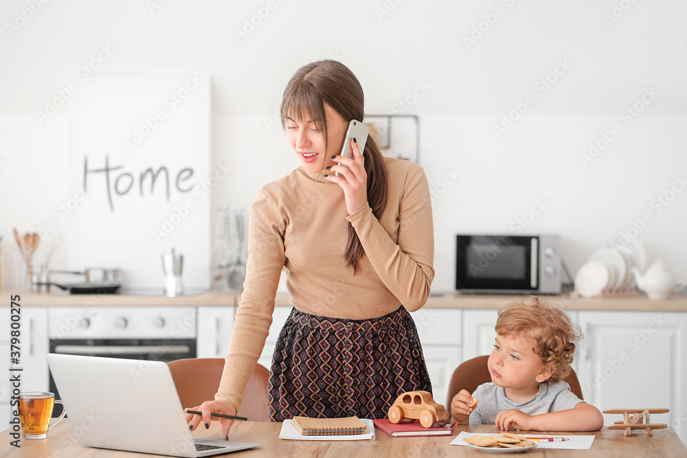 Working mother with little son in kitchen at home