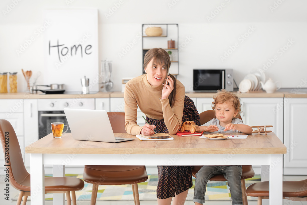 Working mother with little son in kitchen at home