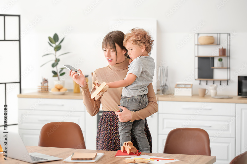 Working mother with little son in kitchen at home