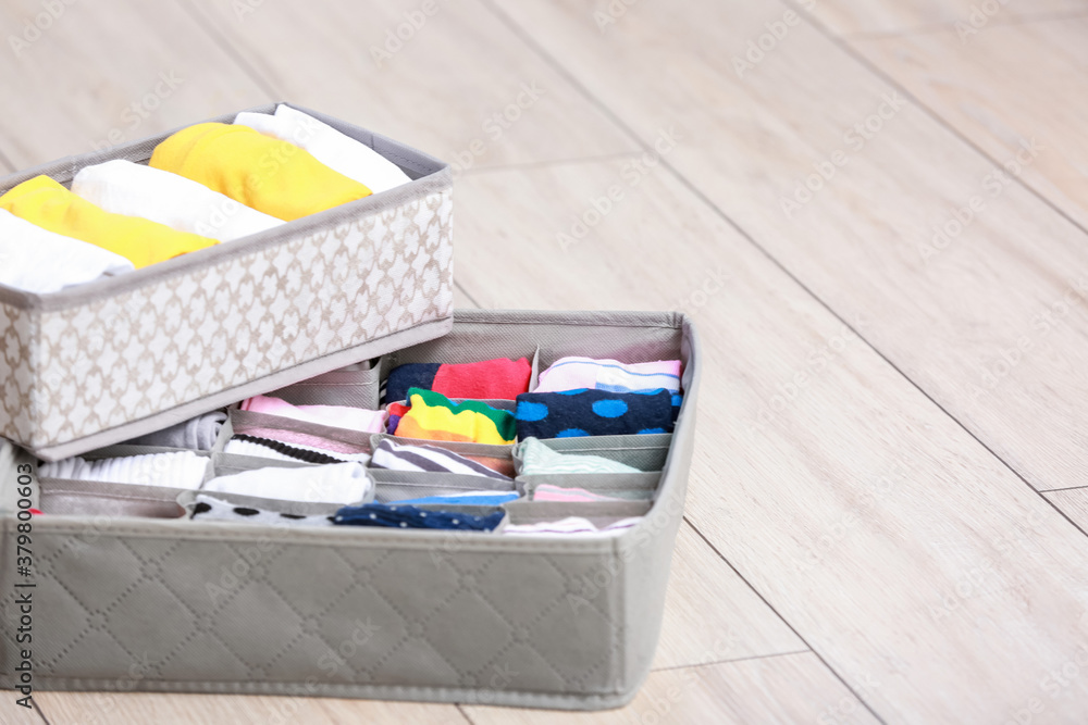 Organizers with clean clothes on wooden floor