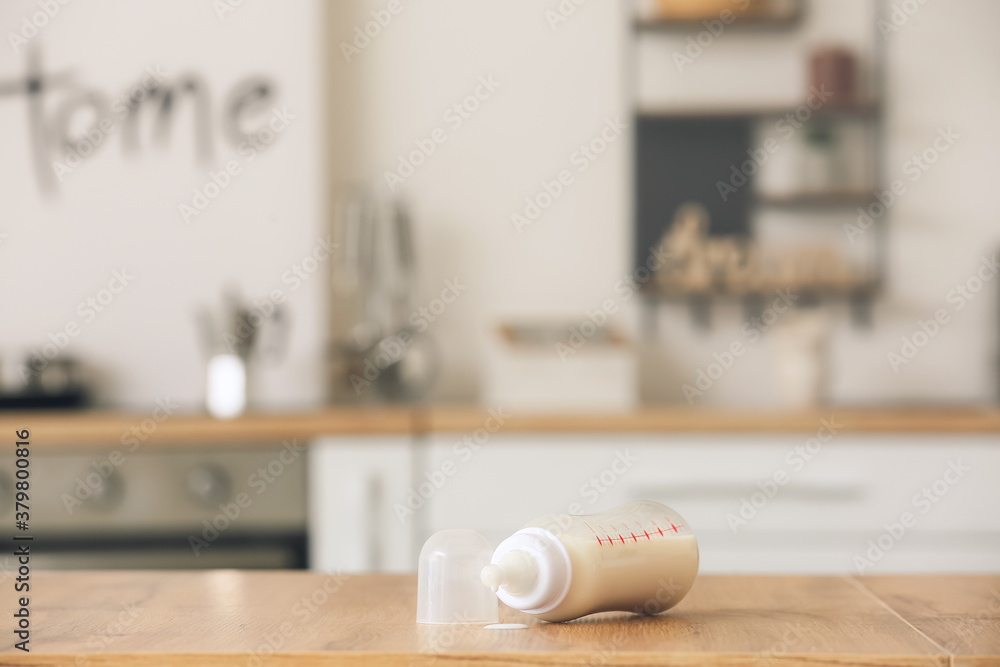 Bottle of milk for baby on table in kitchen