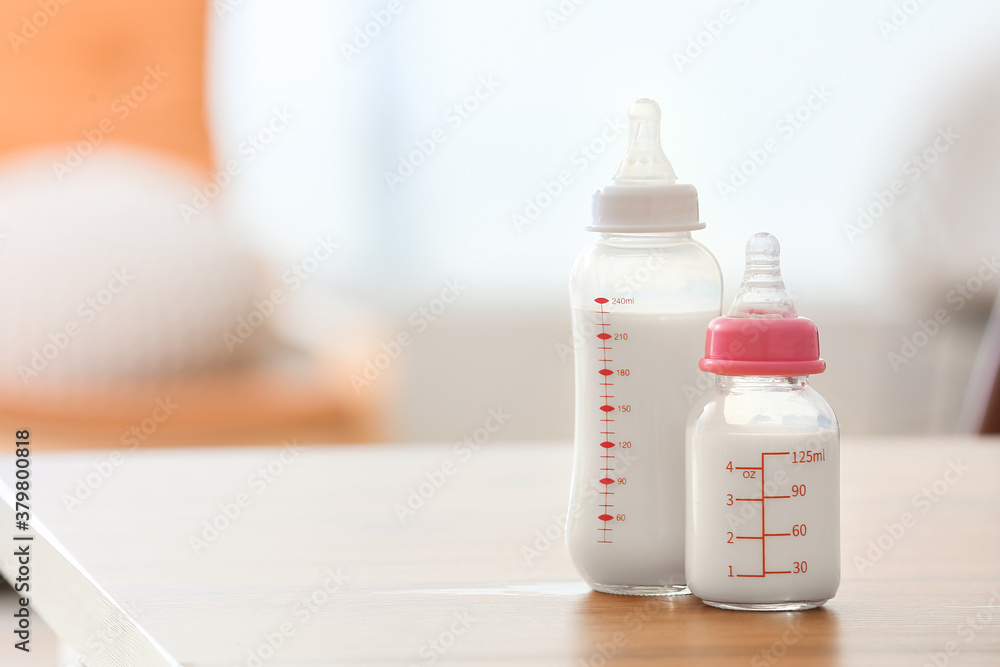 Bottles of milk for baby on table in room