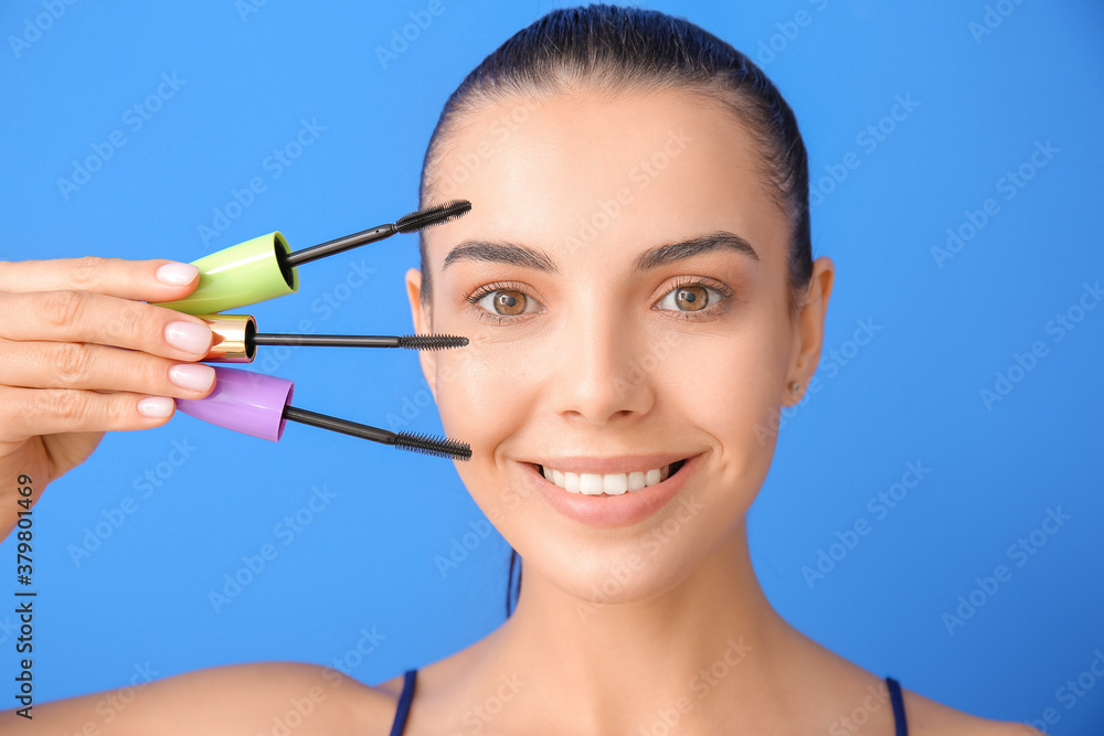 Beautiful young woman with mascara on color background