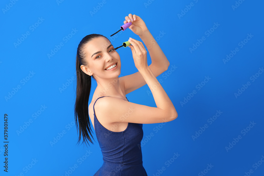 Beautiful young woman with mascara on color background