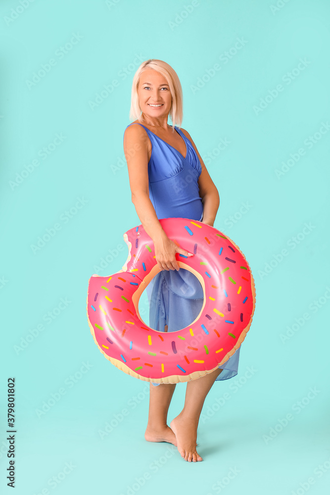 Mature woman with inflatable ring on color background