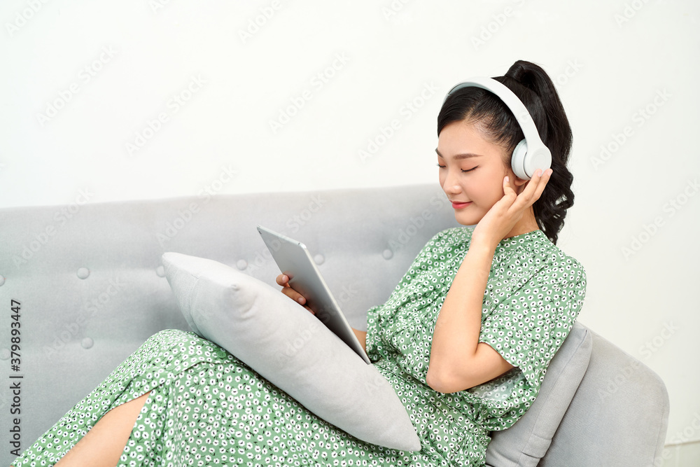 Woman wearing headphones and holding a tablet in a living room