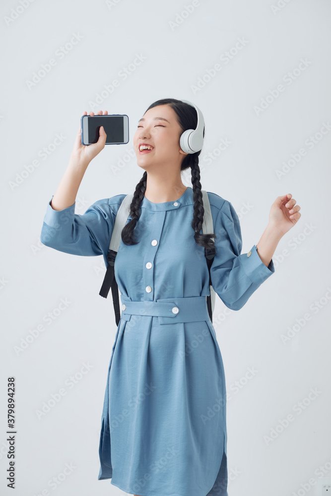 Asian women are listening to music and she sings in the room happily.