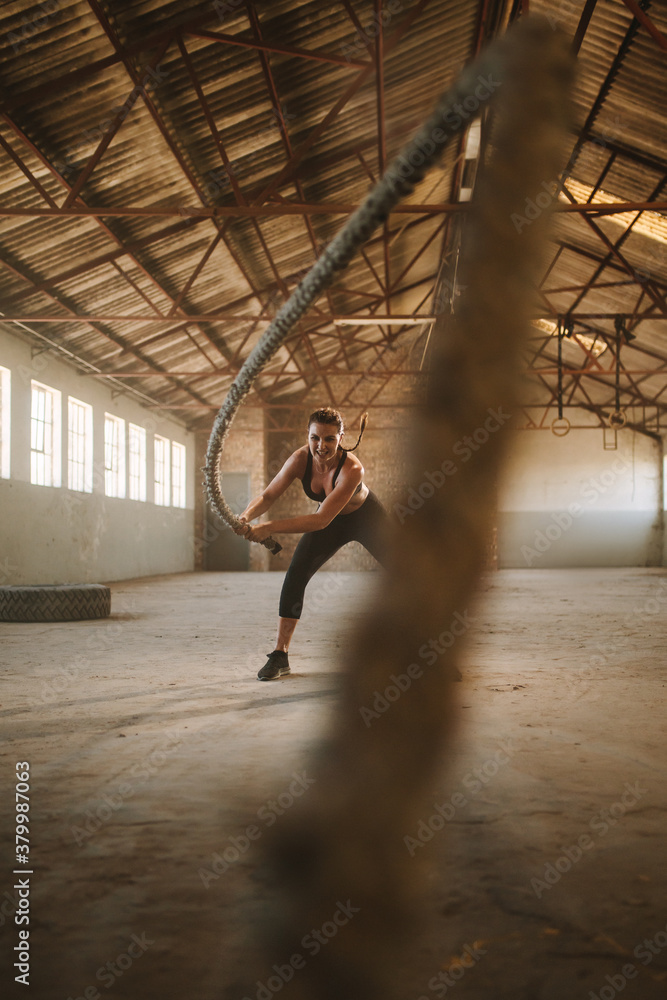 Fitness woman exercising with battle rope