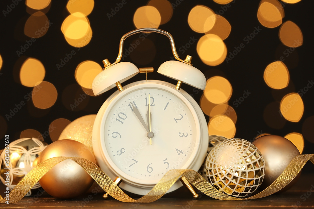 Alarm clock and Christmas decor against blurred lights