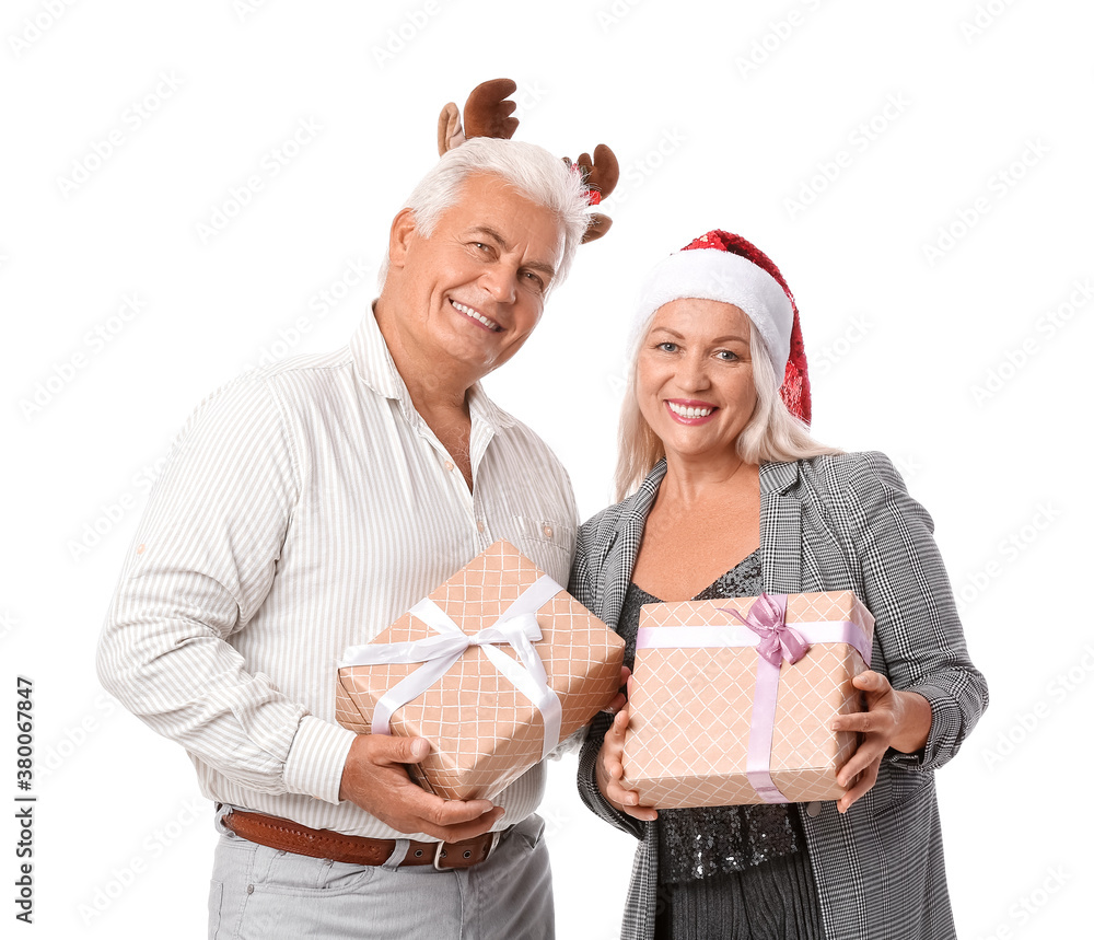 Elderly couple with Christmas gifts on white background