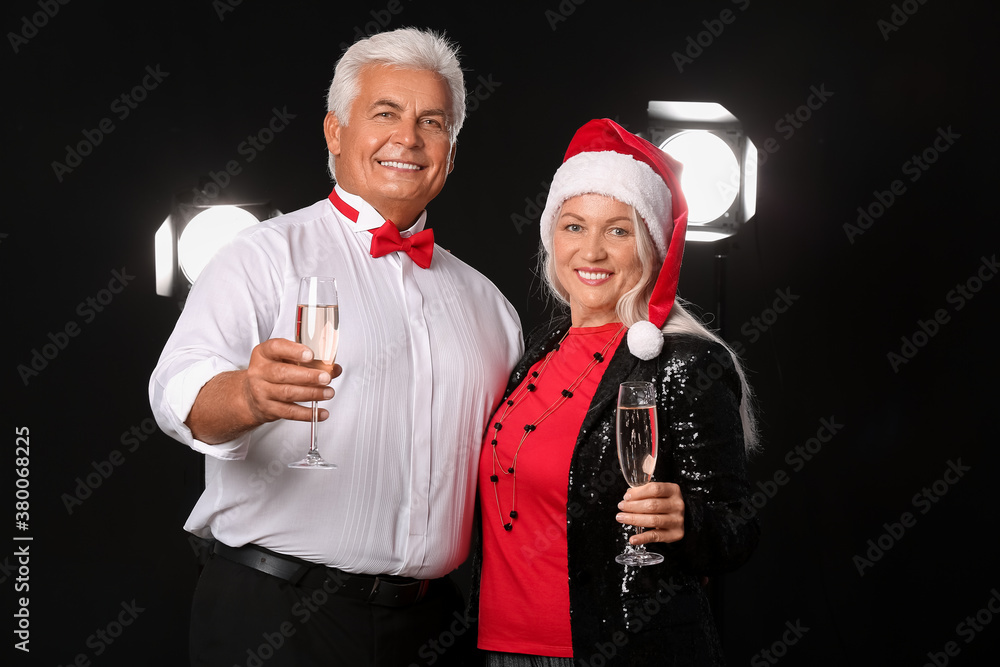 Elderly couple with champagne on dark background. New Year celebration