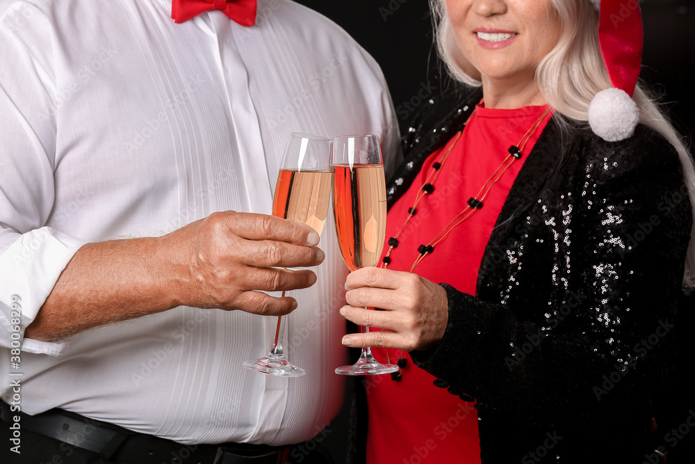 Elderly couple with champagne on dark background. New Year celebration