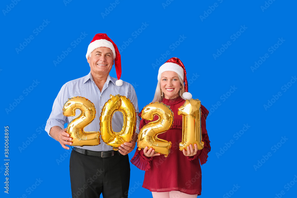 Elderly couple with figure 2021 on color background. New Year celebration