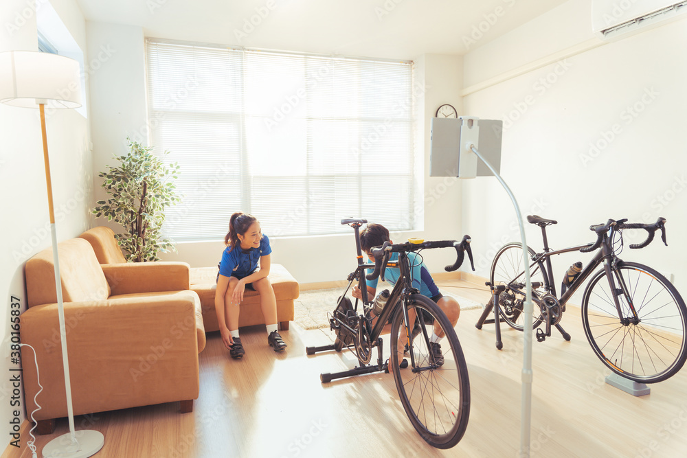 Asian couple. They are preparing bikes on the trainer and play online bike games.