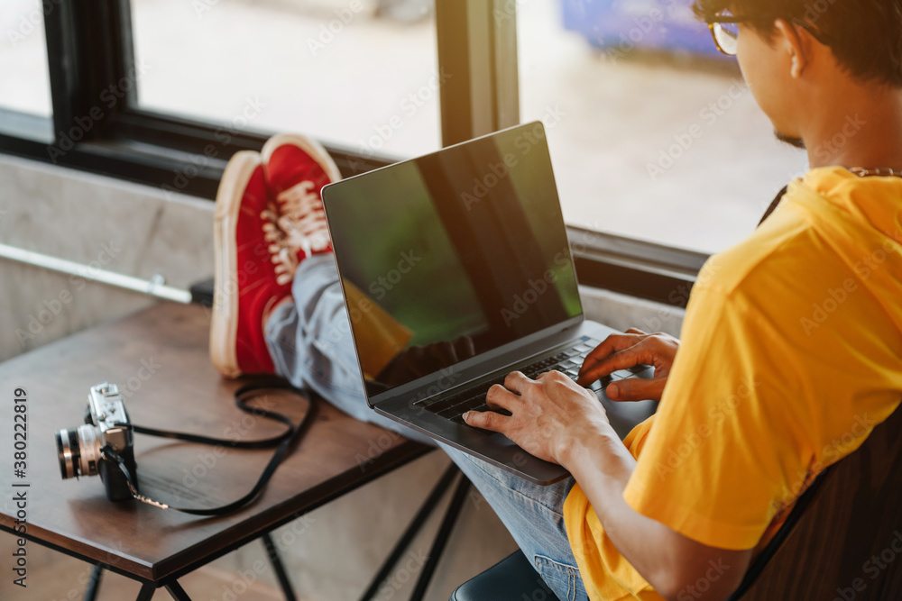 Close up Asian freelance man rewriting content in social network via laptop computer while resting i