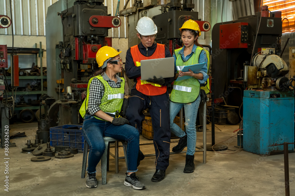 Industrial workers learning work instructions holding laptop computer at factory.