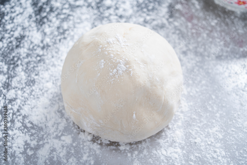 A kneaded dough on a stainless steel chopping board