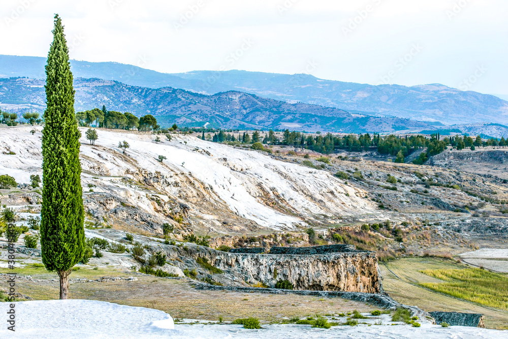 Travertine hill view with blue cloudy sky and fir tree