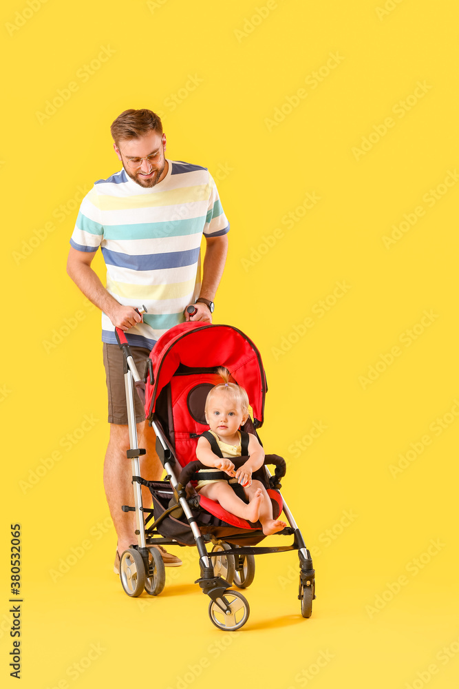 Father and his cute baby in stroller on color background