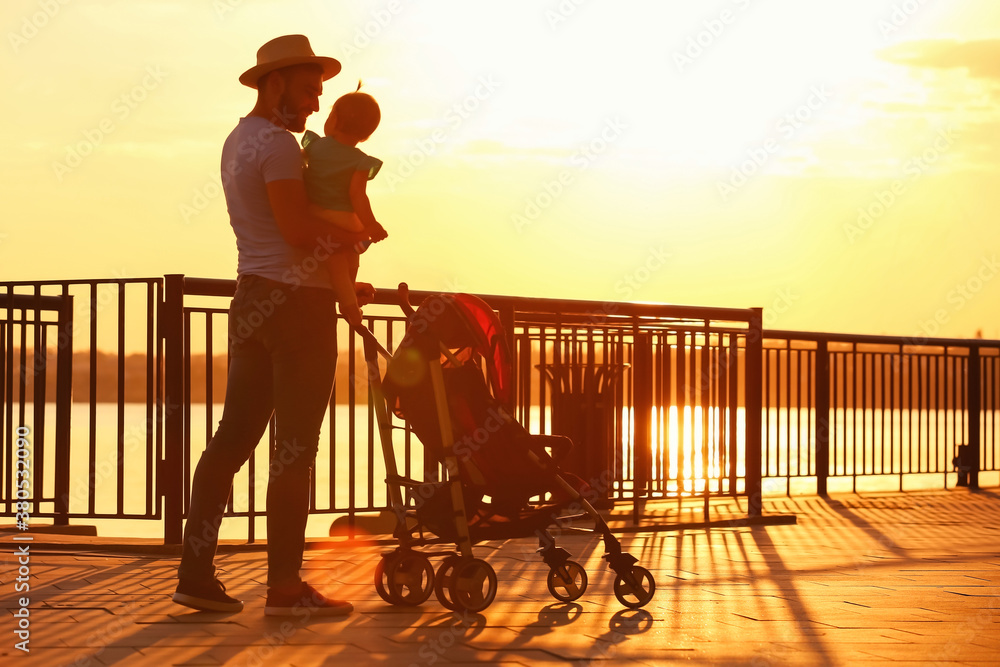 Man and his cute baby in stroller near river