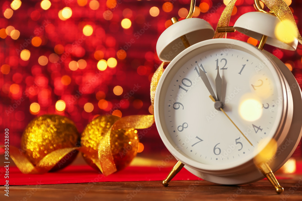 Alarm clock on table against blurred lights. Christmas time