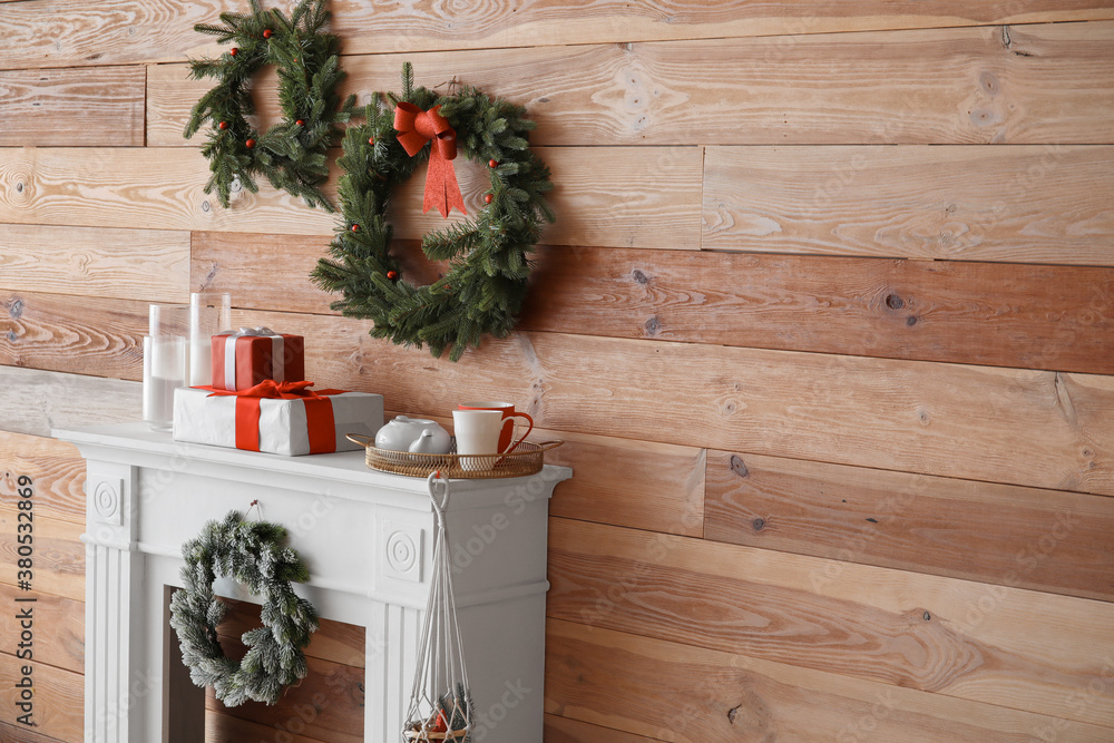 Beautiful Christmas wreaths hanging on wall near fireplace in room