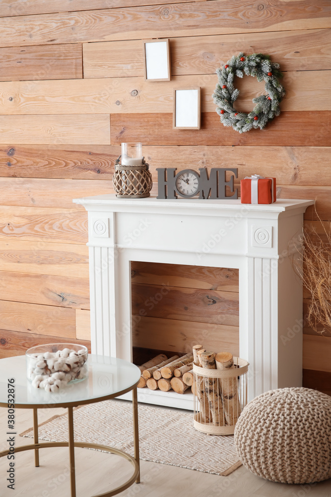 Beautiful Christmas wreath hanging on wall near fireplace in room