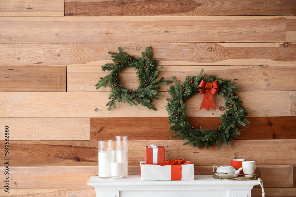 Beautiful Christmas wreaths hanging on wall near fireplace in room