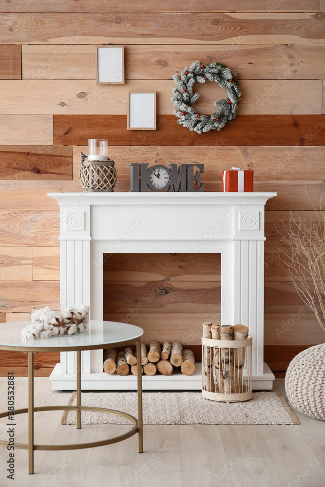 Beautiful Christmas wreath hanging on wall near fireplace in room