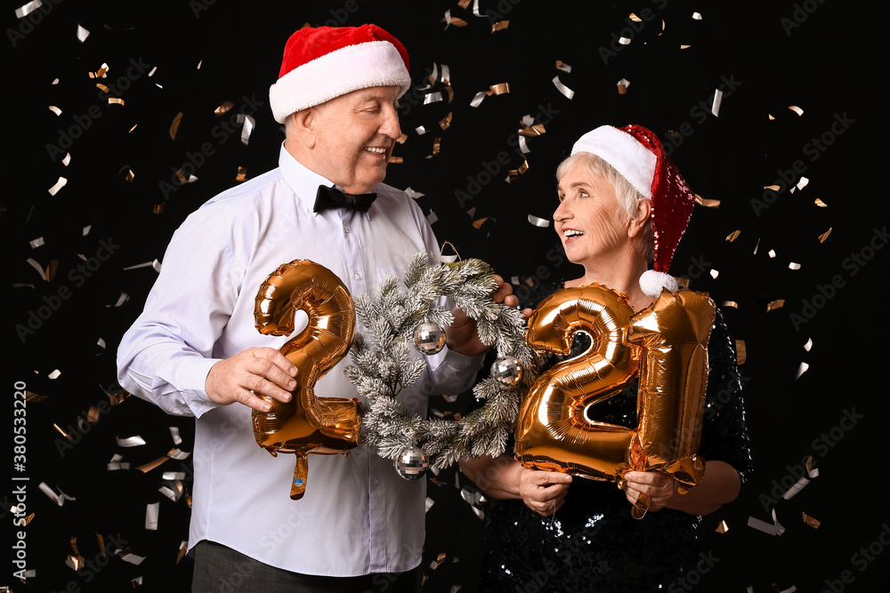 Elderly couple with figure 2021 on dark background. New Year celebration