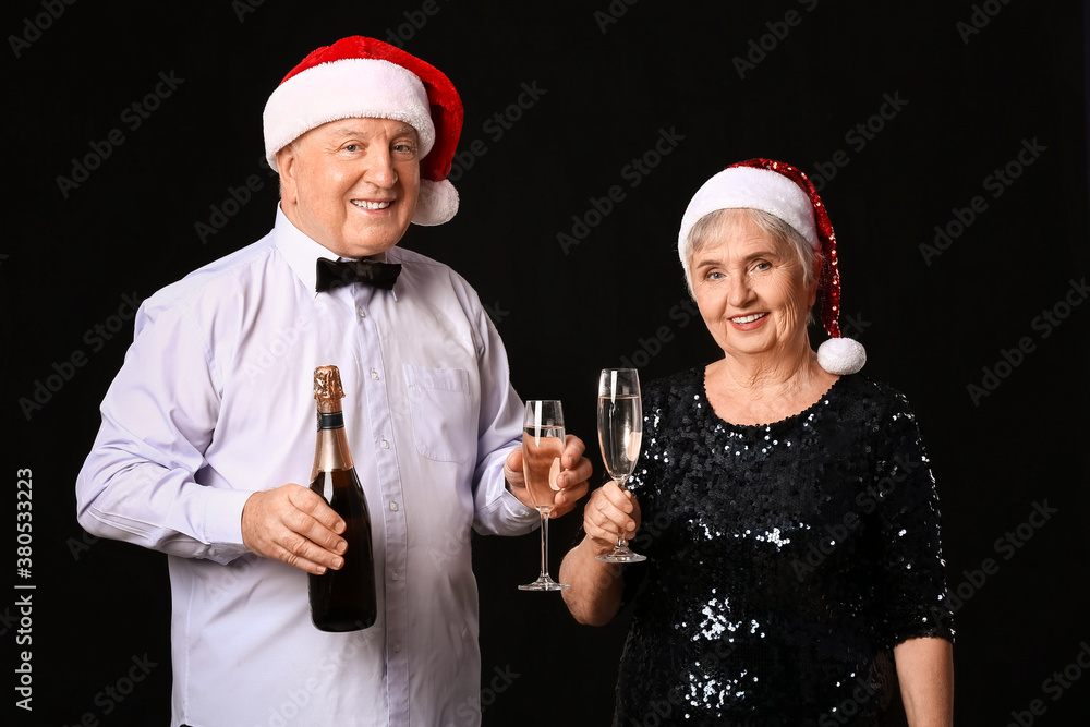 Elderly couple with champagne celebrating Christmas on dark background