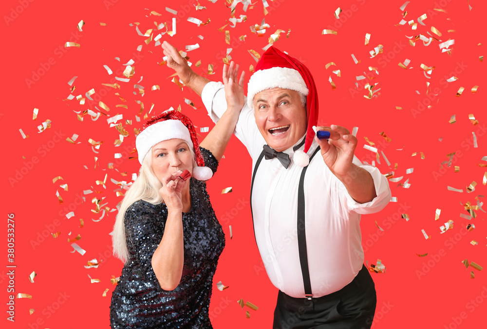 Elderly couple celebrating New Year on color background