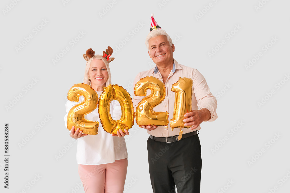 Elderly couple with figure 2021 on light background. New Year celebration