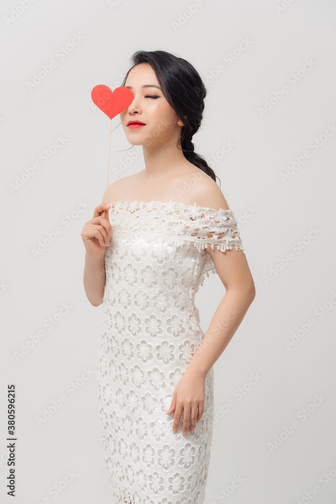 Elegant Asian woman holding a parper heart and standing isolated over white background.