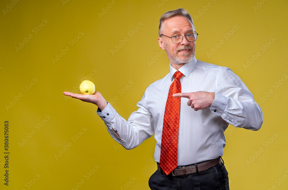 Portrait of handsome senior man posing to the camera. Male is holding an apple in hand. Isolated ove