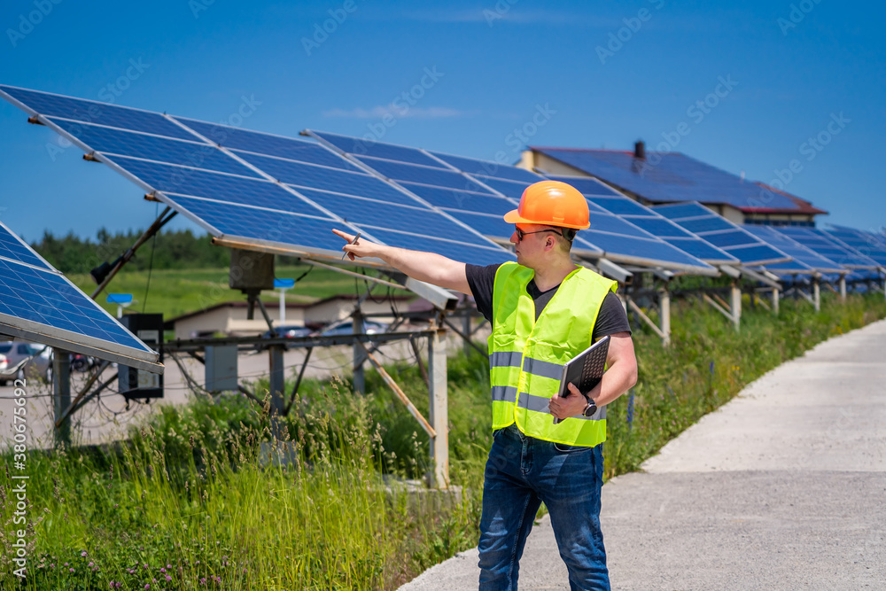 Technician checking efficiency of solar panel at solar power plant. Green energy concept.