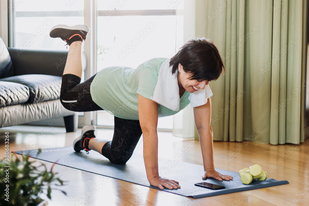 Portrait of a senior brunette woman training gym work out doing exercise at home. Happy mature femal